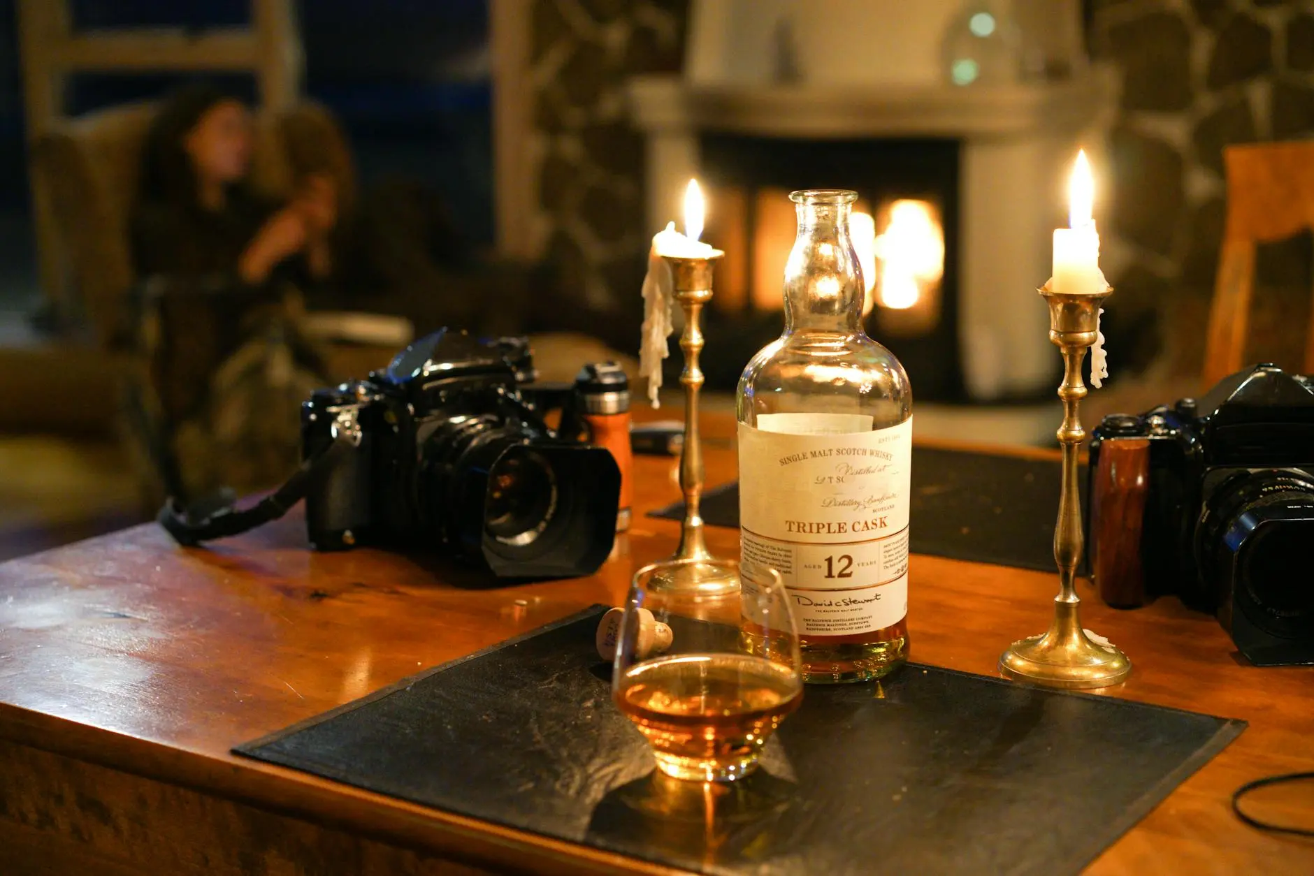 Warm living room setting with whisky, candles, and cameras on a table.
